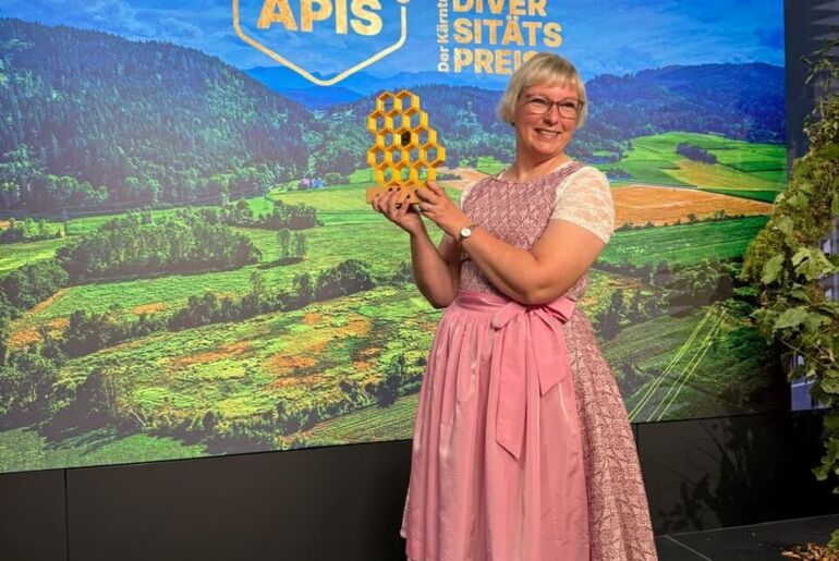 Anita Arneitz mit der Trophäe der Goldenen APIS 2026 auf der Bühne, Kärntner Biodiversitätspreis